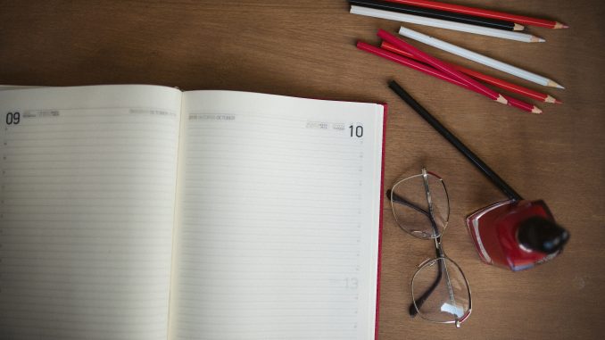 Cuaderno abierto y lápices de colores sobre un escritorio de madera