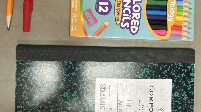 Útiles escolares: cuaderno, lápices, lapiceras, pegamento y tijeras sobre una superficie